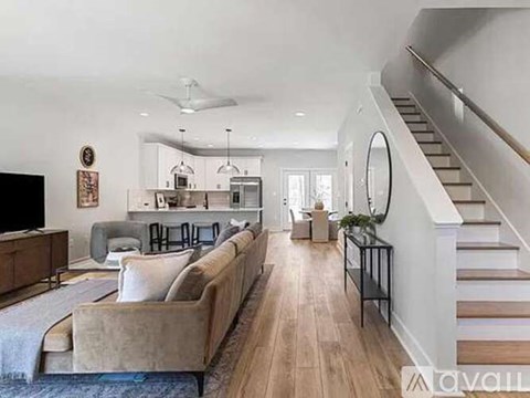 A living room with a couch, a television, and a staircase.