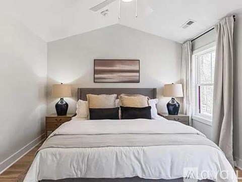 A bedroom with a large bed and a painting above it.