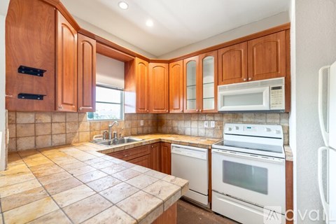 A kitchen with wooden cabinets and a tile countertop.
