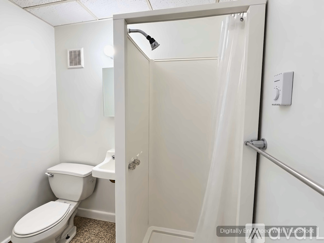 A white toilet is next to a white shower stall in a bathroom.