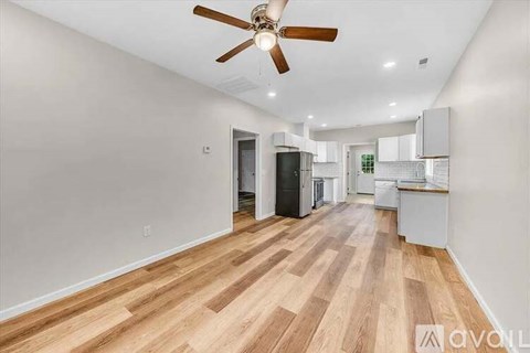 A spacious room with wooden flooring and a ceiling fan.