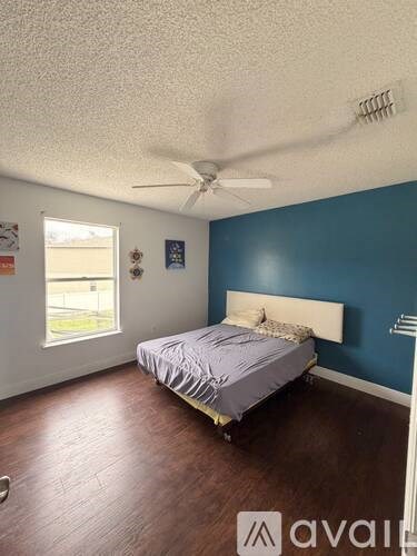 A bedroom with a bed, ceiling fan, and a window.