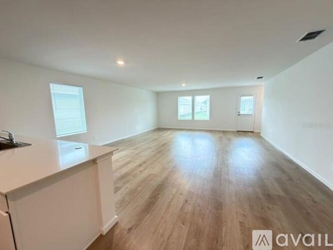 A spacious room with wooden flooring and white walls.