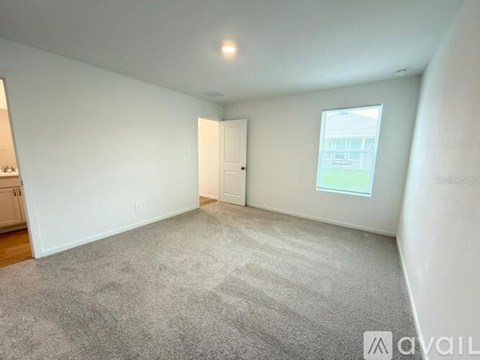 A room with a carpeted floor and a window showing a building outside.