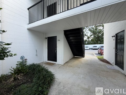 A white building with a black door and a balcony.