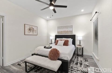 A bedroom with a white bed and a ceiling fan.