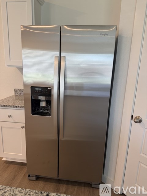 A Whirlpool refrigerator with a water and ice dispenser in the middle of the door.