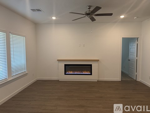 A living room with a fireplace and a ceiling fan.