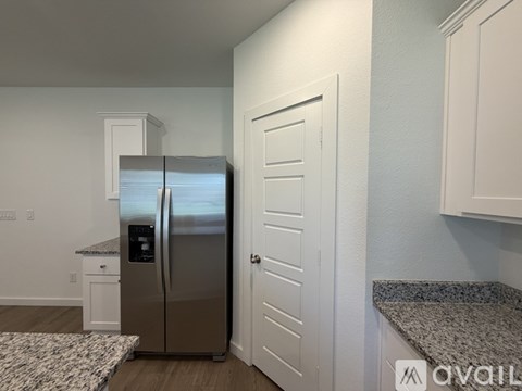 A kitchen with a stainless steel refrigerator and white cabinets.