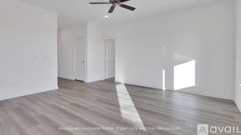 A spacious room with a ceiling fan and light wood flooring.