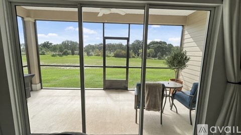 A patio with a table and chairs overlooks a grassy field.