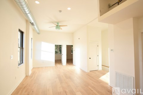 A spacious room with wooden floors and a ceiling fan.