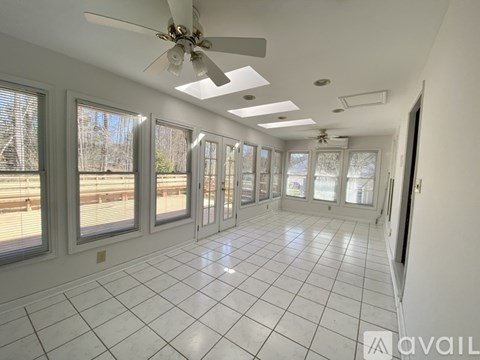 A spacious room with a ceiling fan and large windows.