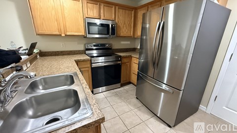 A kitchen with a stainless steel refrigerator, sink, and stove.