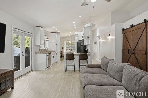 A modern living room with a grey sofa and a kitchen in the background.