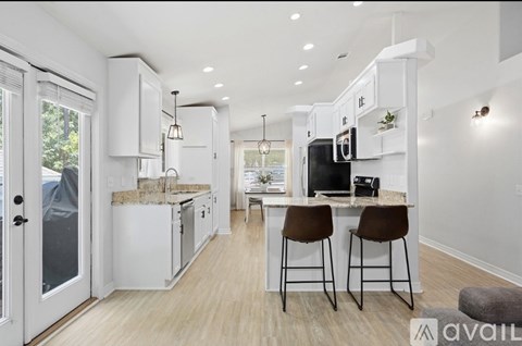 A kitchen with white cabinets and a bar area with stools.