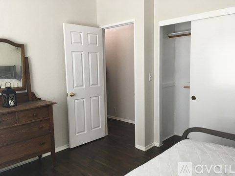 A bedroom with a white door and a wooden dresser.