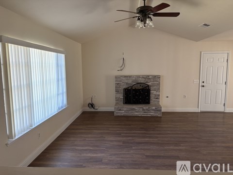 A living room with a fireplace and a ceiling fan.