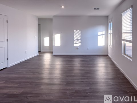 A spacious room with wooden flooring and white walls.