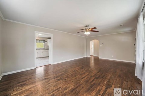 A spacious room with wooden floors and a ceiling fan.
