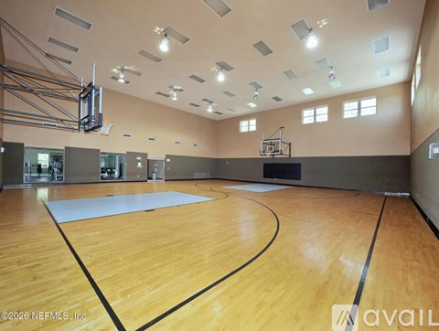 A basketball court inside a gymnasium with a wooden floor and a basketball hoop.