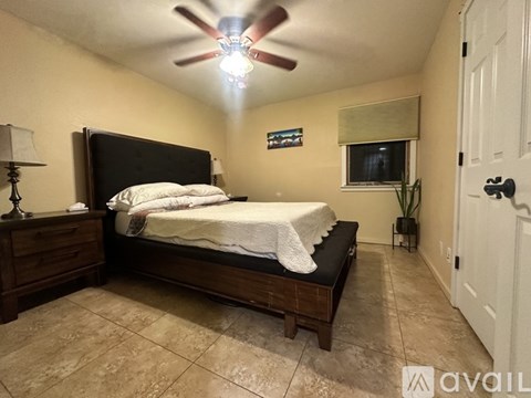 A bedroom with a bed, nightstand, and a ceiling fan.