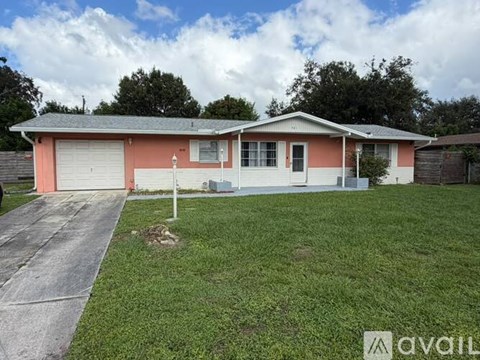 A pink house with a white garage door is for sale.