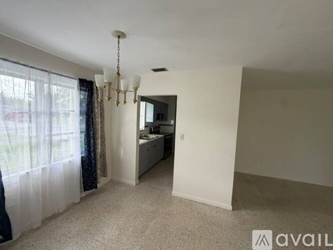 A room with a chandelier and a window with curtains.