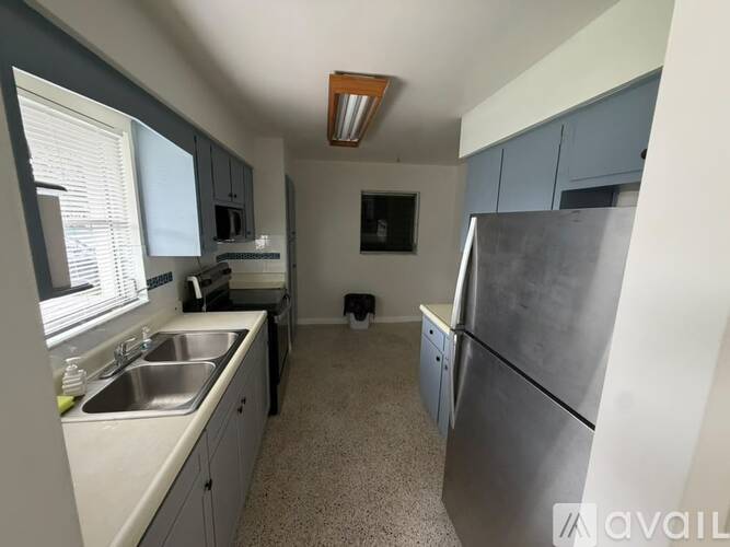 A kitchen with a refrigerator, sink, and cabinets.