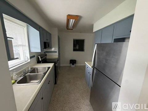 A kitchen with a refrigerator, sink, and cabinets.