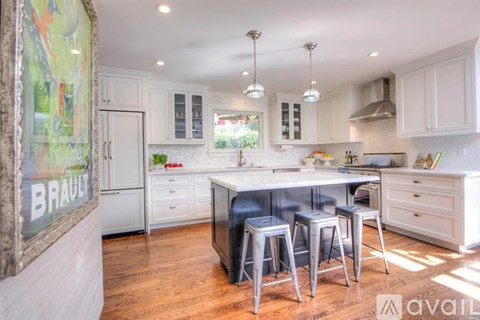 A kitchen with white cabinets and a large island with bar stools.