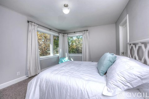 A bedroom with a large bed and a window with curtains.
