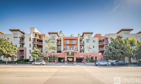 A row of modern apartment buildings with cars parked in front.