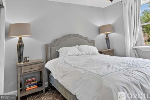 A bedroom with a large bed and a nightstand with a lamp.