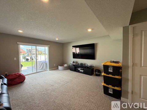 A living room with a flat screen TV mounted on the wall and a red bean bag chair.