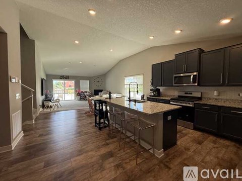 A kitchen with black cabinets and a wooden floor.