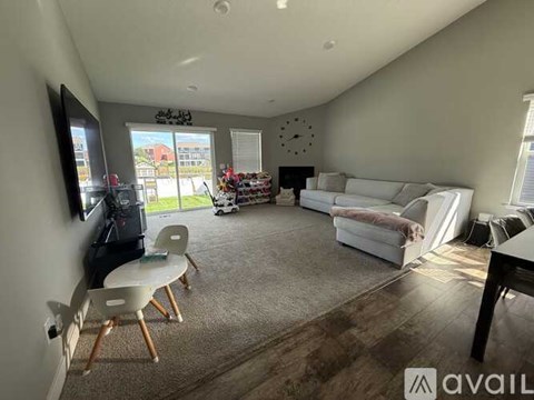A living room with a white couch, a television, and a clock on the wall.