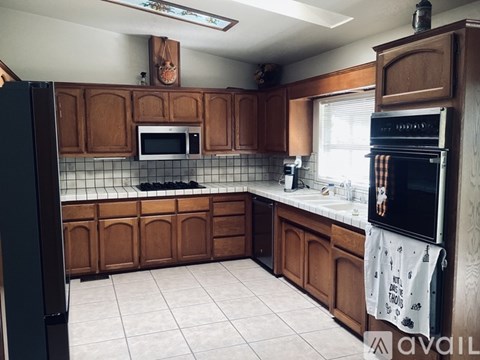 A kitchen with brown cabinets and a black refrigerator.