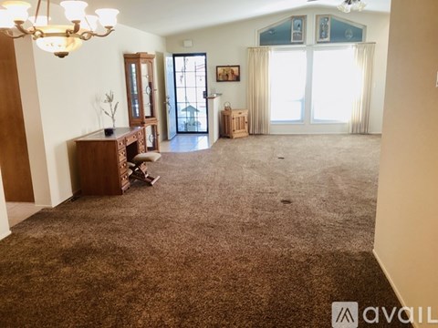 A living room with a brown carpet and a chandelier.