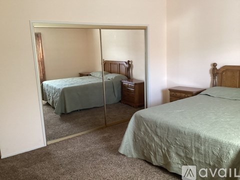 A bedroom with two beds and a mirror.