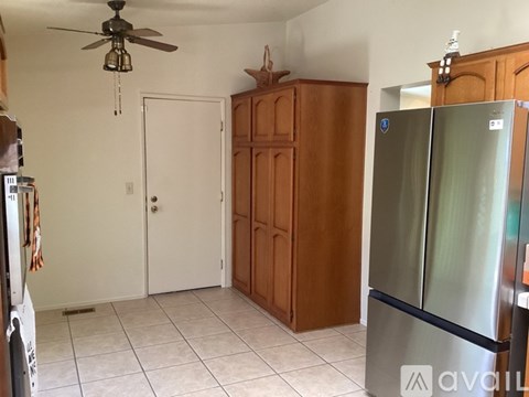 A kitchen with a refrigerator, wooden cabinets, and a ceiling fan.