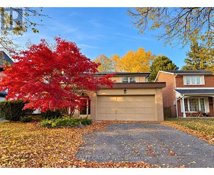 A red maple tree in front of a house with a garage.