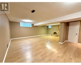 A spacious room with wooden flooring and a fireplace.