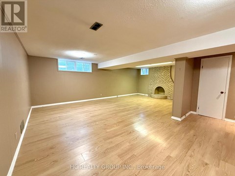 A spacious room with wooden flooring and a fireplace.