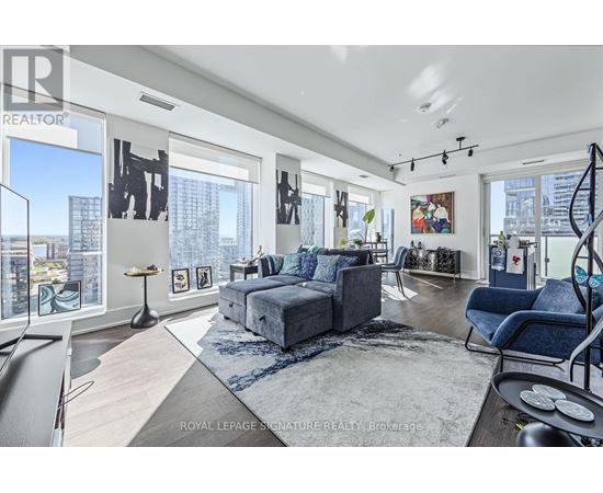 A spacious living room with a grey sofa set and a large window overlooking the city.