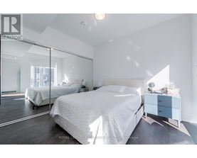 A bedroom with a large bed and a mirrored wall.