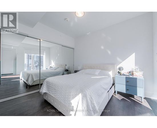 A bedroom with a large bed and a mirrored wall.