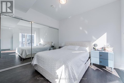A bedroom with a large bed and a mirrored wall.