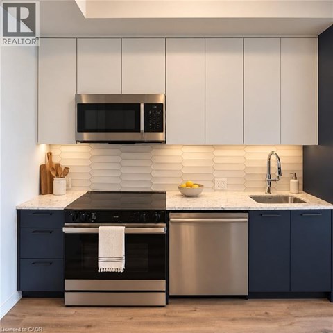 A modern kitchen with a stainless steel oven and microwave above a sink.