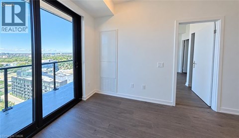 A room with a sliding glass door leading to a balcony with a view of the city.